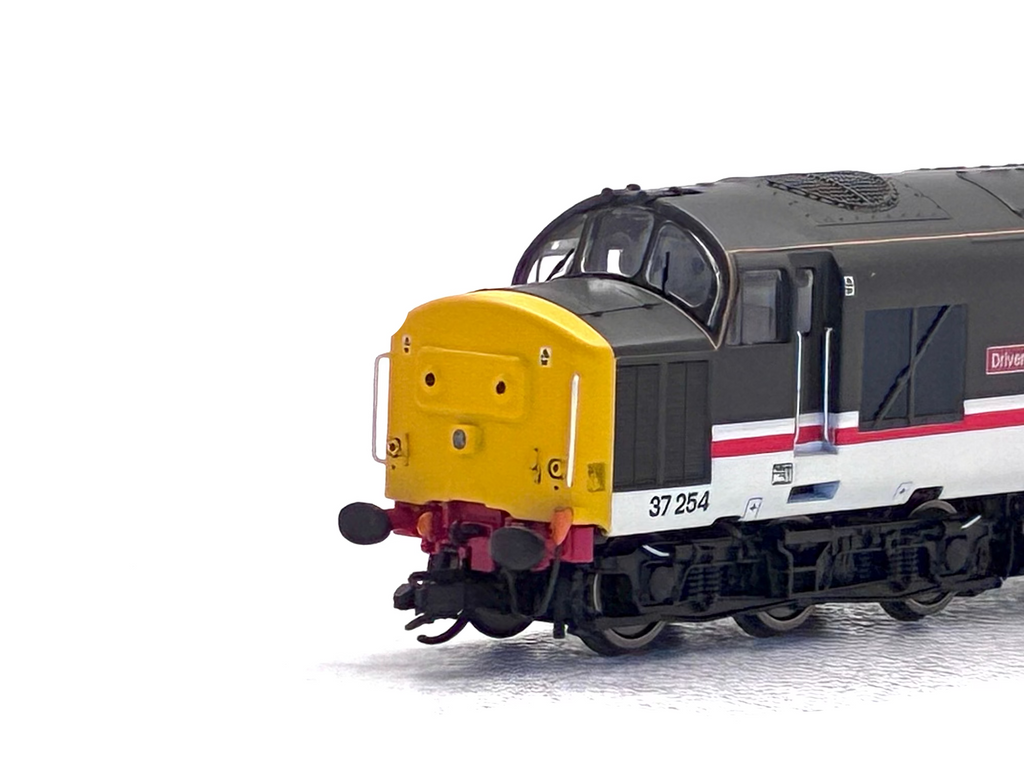 A model train locomotive photographed on a plain white background. The train has a black upper body, a bright yellow front face, a white lower body panel, and red stripe accents.