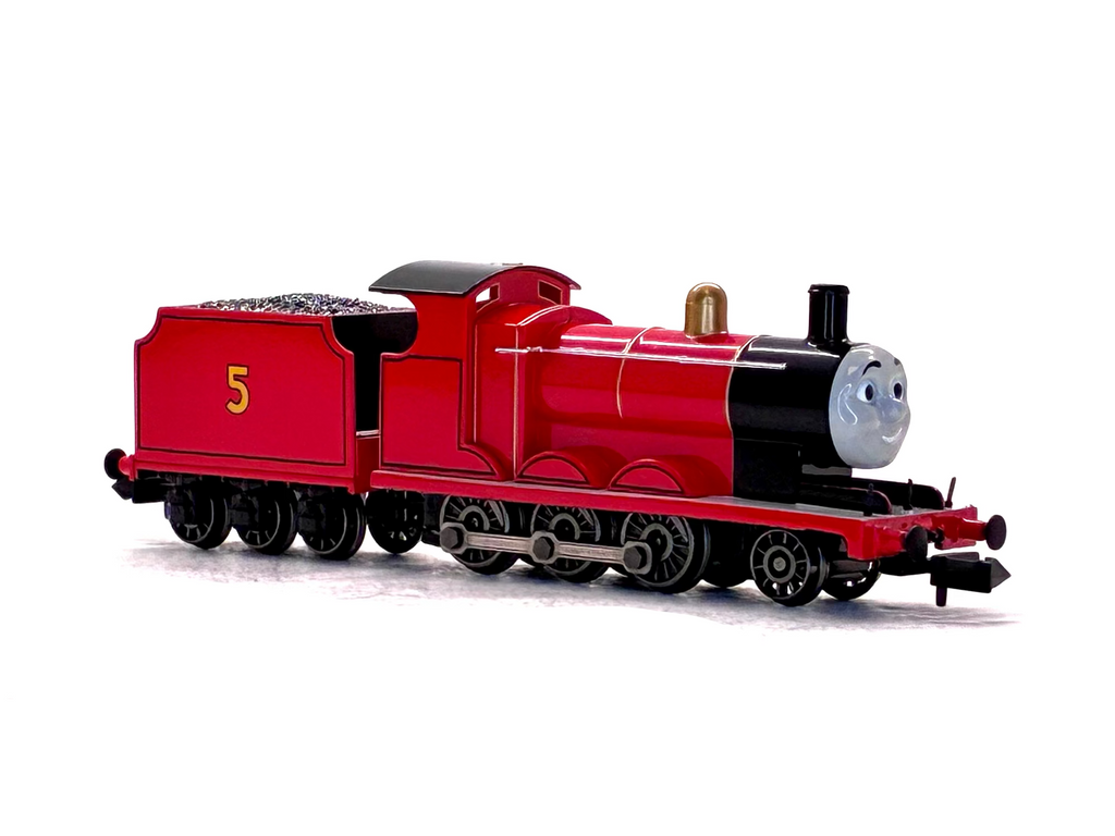 James Thomas the Tank Engine style toy train locomotive with a smiling gray face on the front, photographed on a plain white background.