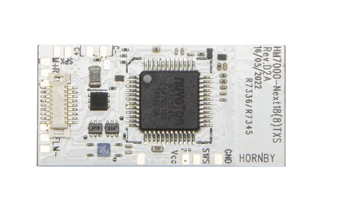 A rectangular electronic circuit board with a large black central microchip, various small electronic components, and printed text including 'HORNBY' and 'PEL' on a white background.