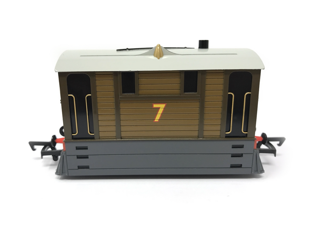 A detailed model of Toby the tram, specifically designed to resemble 7, featuring brown wood paneling, a cream-colored roof, a yellow number 7 on the front, and a dark gray underframe, set against a plain white background.