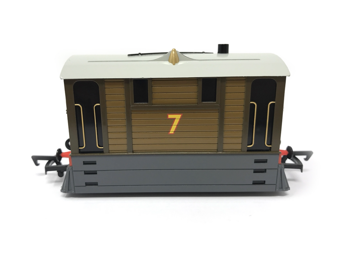 A detailed model of Toby the tram, specifically designed to resemble 7, featuring brown wood paneling, a cream-colored roof, a yellow number 7 on the front, and a dark gray underframe, set against a plain white background.
