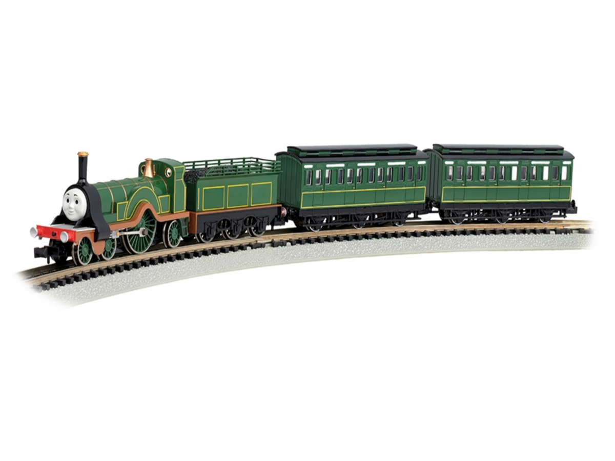 Emily model train with a smiling face on the front, pulling two matching green passenger cars along a curved track against a white background.