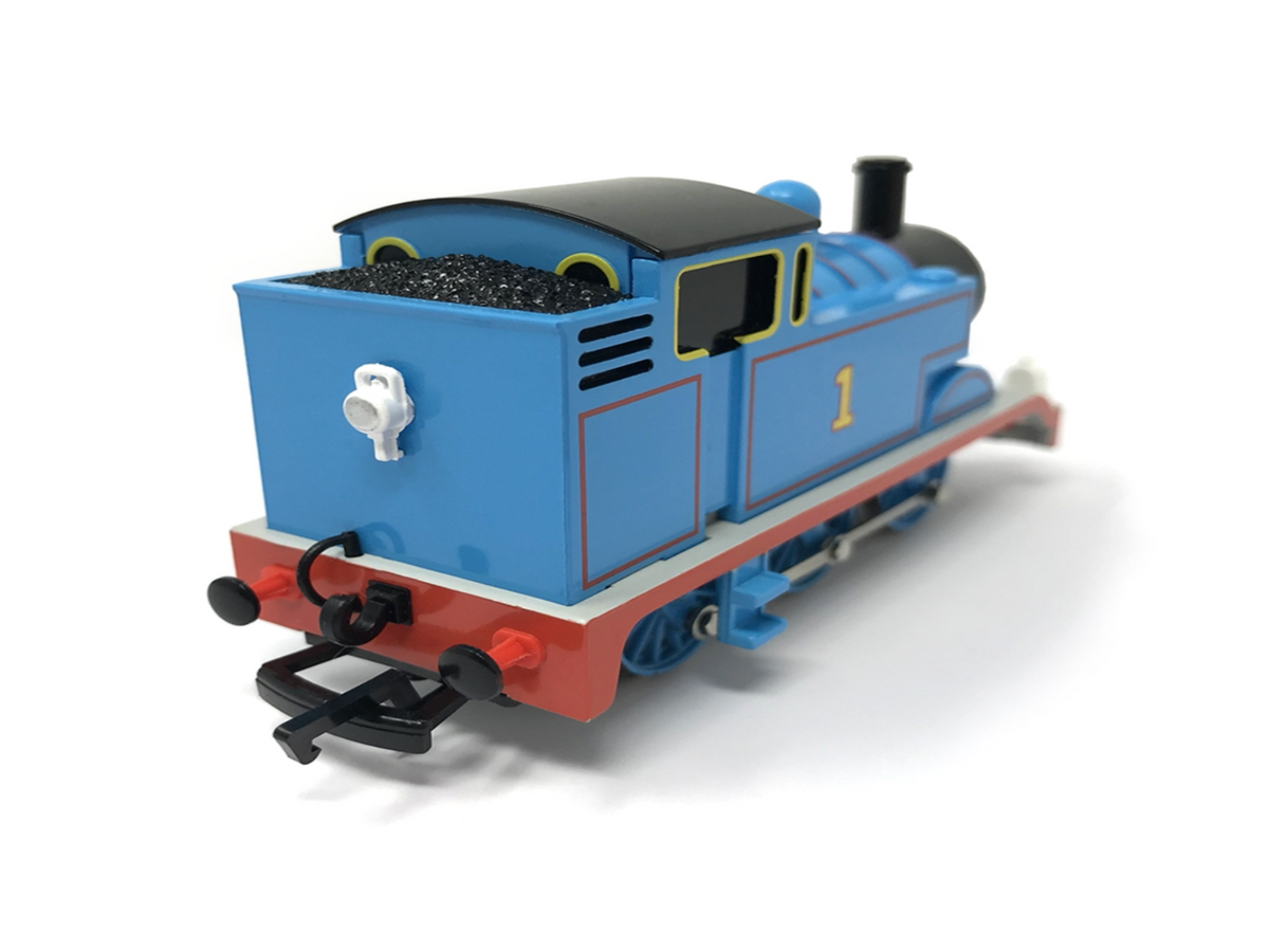 A Thomas the Tank Engine toy train, shown from a three-quarters rear angle. The toy features its signature blue body, red buffer striping, black smokestack and coal bunker, and a yellow number 1 on the side.
